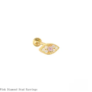 Close-up macro detail of golden evil eye cartilage stud with pink diamond center