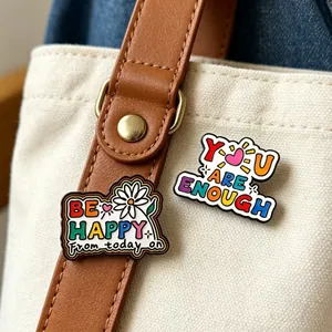 Macro detail of colorful metal enamel brooches with positive quotes on a canvas bag