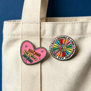 Detailed view of colorful enamel pins with mental health quotes on a canvas bag