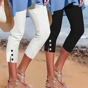 Detail view of women's cropped leggings featuring button accents and hem slits on the beach.