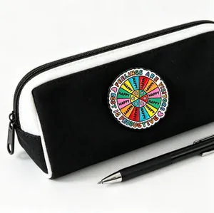 Macro view of a colorful motivational enamel pin attached to a black and white pencil case.