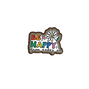 Colorful enamel pin featuring 'BE HAPPY' motivational quote and a small white daisy