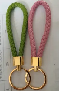 Detailed view of green and pink braided PU leather keychains with shiny gold rings