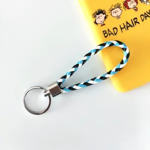 Détail d'un porte-clés en cordon de cuir PU tressé bleu, blanc et noir