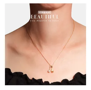 Close-up detail of a delicate gold spoon and fork pendant necklace worn by a model.