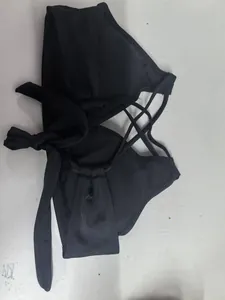 Dettaglio del top bikini nero con spalline incrociate sul retro e nodo laterale decorativo.