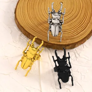 Dettaglio di anelli scarabeo creativi in finiture oro, argento e nero
