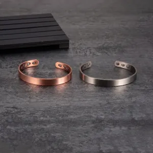 Gros plan de deux bracelets magnétiques en cuivre pur mat, tons cuivre et argent.