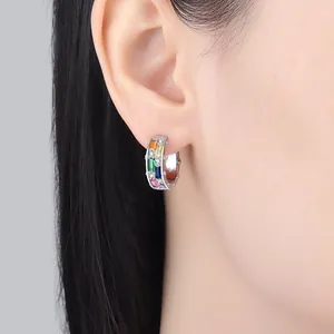 Primo piano di orecchini a cerchio geometrici con pietre arcobaleno e ago d'argento.
