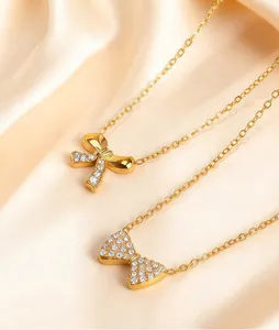 Two gold-plated bow necklaces on silk, highlighting delicate 304 stainless steel craftsmanship