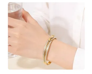 Gros plan d'un bracelet jonc doré au design de fermeture éclair orné de cristaux