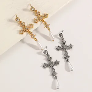 Primo piano di eleganti orecchini a croce gotica in oro e argento con perle a goccia