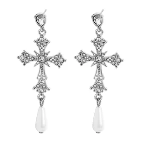 Dettaglio di orecchini a croce gotica in argento vintage con motivi floreali e perle