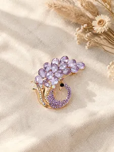 Primo piano dettagliato di una spilla a pavone viola con strass a forma di pera