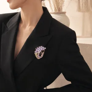 Elegante spilla a pavone viola con cristalli scintillanti su blazer nero da donna