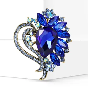 Close-up of elegant heart-shaped brooch with blue crystals and teardrop centerpiece
