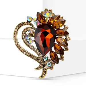 Close-up detail of a vintage heart brooch featuring a large amber teardrop glass stone