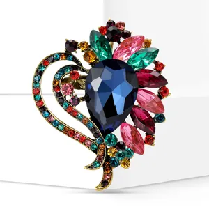 Detail shot of a vintage colorful heart brooch with vibrant rhinestones and blue center stone.