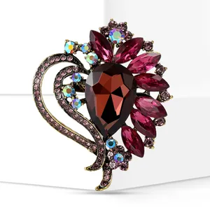 Macro detail of a vintage heart brooch with deep red glass gems and iridescent crystals.