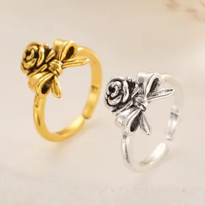 Close-up of elegant gold and silver rose flower bow rings with adjustable open band.