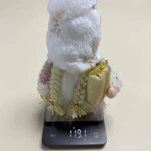 Detailed view of a plush white Christmas gnome on a digital scale weighing 119.1g