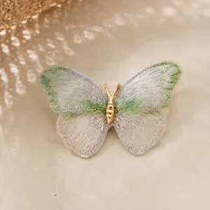 Detailed macro view of a handmade embroidered butterfly brooch with gold-tone accents