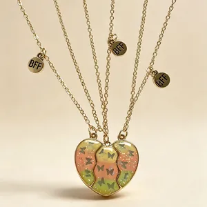 Détail du collier de cœur magnétique avec des motifs papillons scintillants et tags BFF.