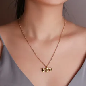 Close-up detail of a vintage style antique gold bat pendant necklace worn by a model.