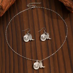 Vintage western cowboy theme jewelry set with hat and boot charms on dark wood background