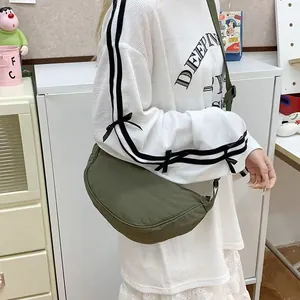 Detailed view of a minimalist olive green canvas crescent bag worn as a crossbody by model