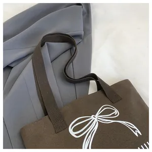 Detailaufnahme einer braunen Canvas-Tasche mit Schleifendruck und stabilen Trägern.