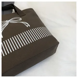 Nahaufnahme einer braunen Canvas-Tasche mit weißer Schleife und vertikalen Streifen