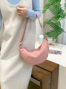 Chic pink crescent-shaped dumpling shoulder bag styled as a versatile canvas crossbody purse.