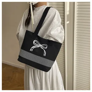 Schwarze Canvas-Umhängetasche mit weißem Schleifendesign und gestreiftem Muster