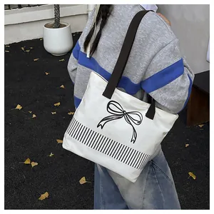 Nahaufnahme einer weißen minimalistischen Segeltuchtasche mit schwarzem Schleifendesign auf Modell