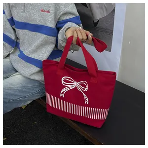 Detailansicht einer roten Segeltuchtasche mit minimalistischem weißen Schleifen- und Streifendesign