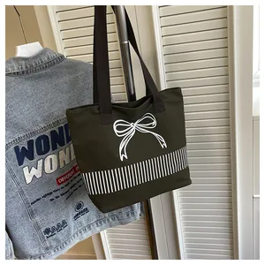 Dunkelgrüne minimalistische Canvas-Einkaufstasche mit weißem Schleifen-Design im Lifestyle
