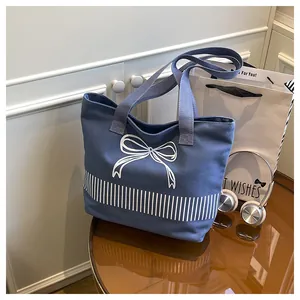 Blaue Canvas-Schultertasche mit weißem Schleifen-Design in Lifestyle-Umgebung