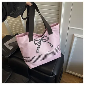 Nahaufnahme einer rosa Leinentasche mit schwarzem Schleifendruck und Streifendetails.