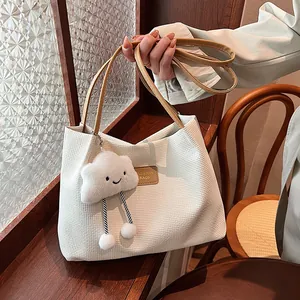 Detailed view of a white waffle textured tote bag featuring a cute smiley cloud plush charm