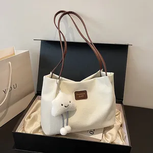 Detailed view of white corduroy textured tote bag with FASHION BAGS patch and cloud keychain