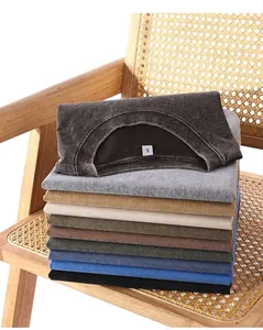 Pile de t-shirts vintage délavés et épais de différentes couleurs sur une chaise en rotin