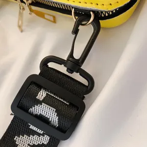 Detailaufnahme des schwarzen Verschlusses und des Riemens einer gelben Box-Tasche
