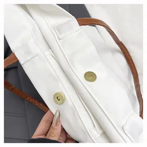 Close-up view of the sturdy magnetic snap closure on a white canvas bucket bag.