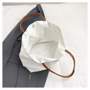 Internal view of a white canvas bucket bag showing the small pocket and magnetic button