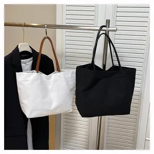 Large capacity canvas tote bags in white and black displayed on a clothes rack
