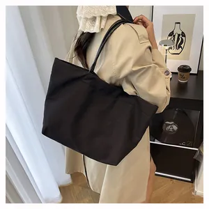 Minimalist black canvas tote bag shown on model in a stylish interior lifestyle setting