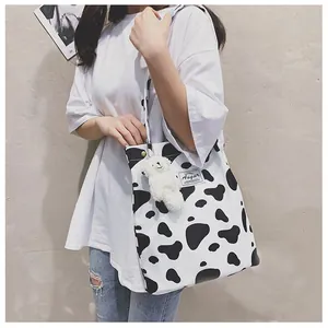 Modèle asiatique portant un sac cabas chic imprimé vache noir et blanc élégant