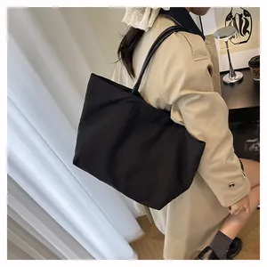 Black large capacity canvas tote bag carried by a woman in a stylish beige trench coat