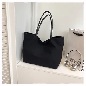 Stylish black canvas tote bag with large capacity shown in a clean minimalist scene